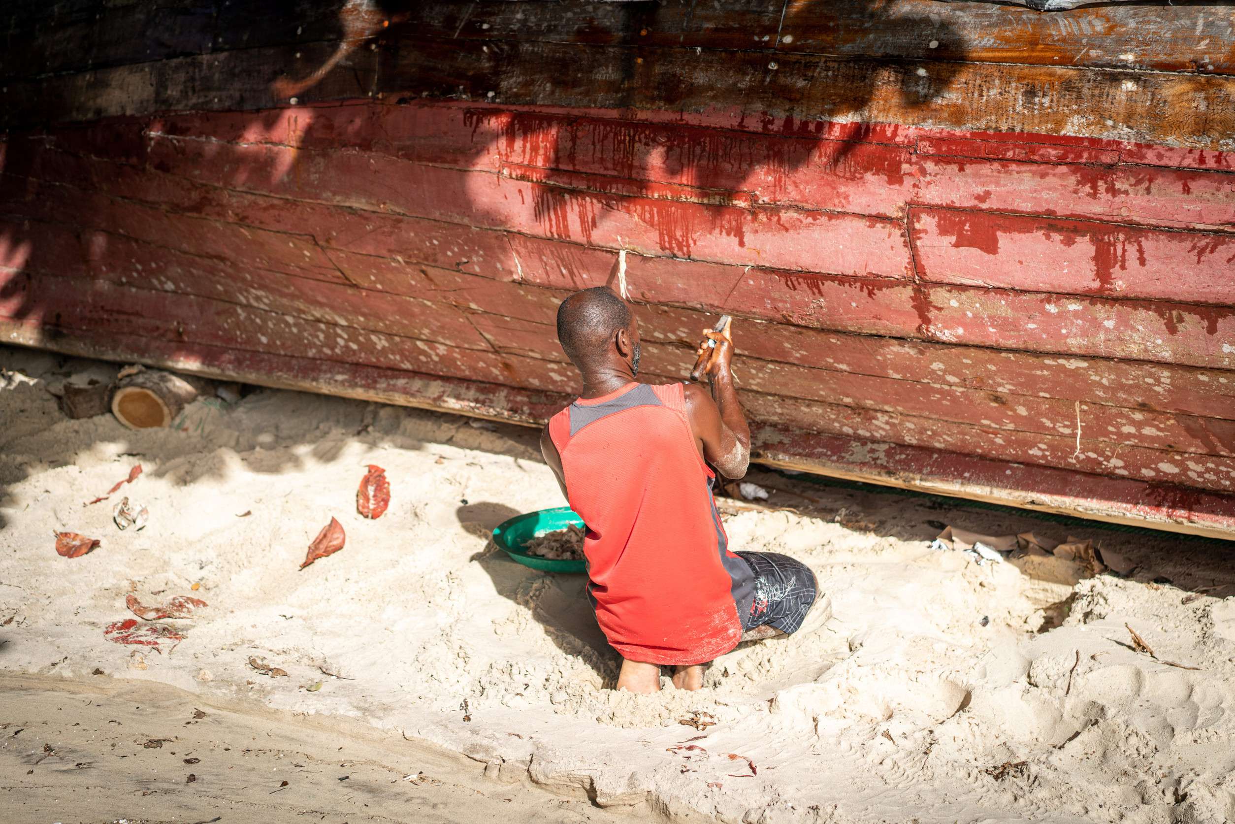 An African Fisherman Repairs His Boat On The Beach