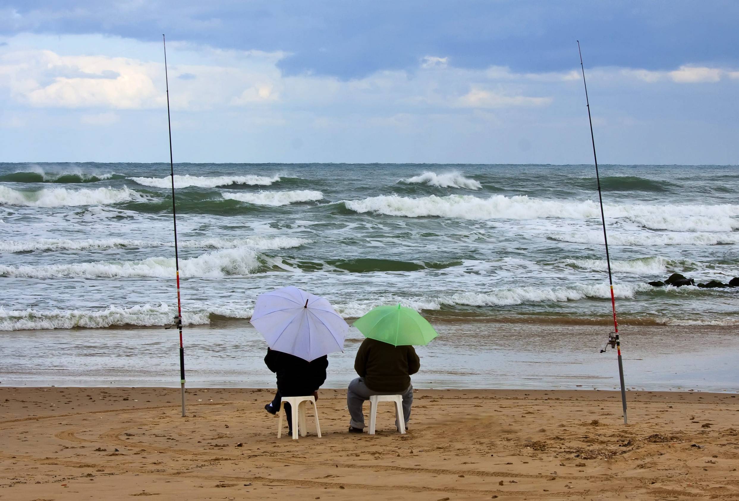 Two Fishermen With Umbrellas